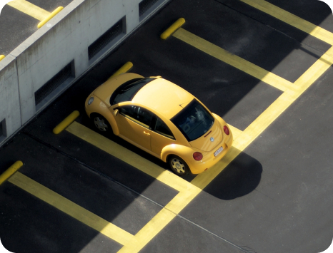 A photo shows a yellow Volkswagen Beetle parked in a parking lot.